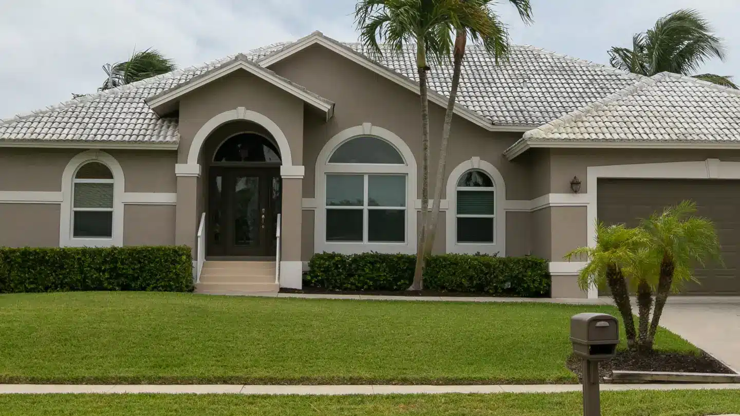 Large brown house with brown windows and a palm tree outside and grass lawn. Large brown house with brown windows and a palm tree outside and grass lawn.