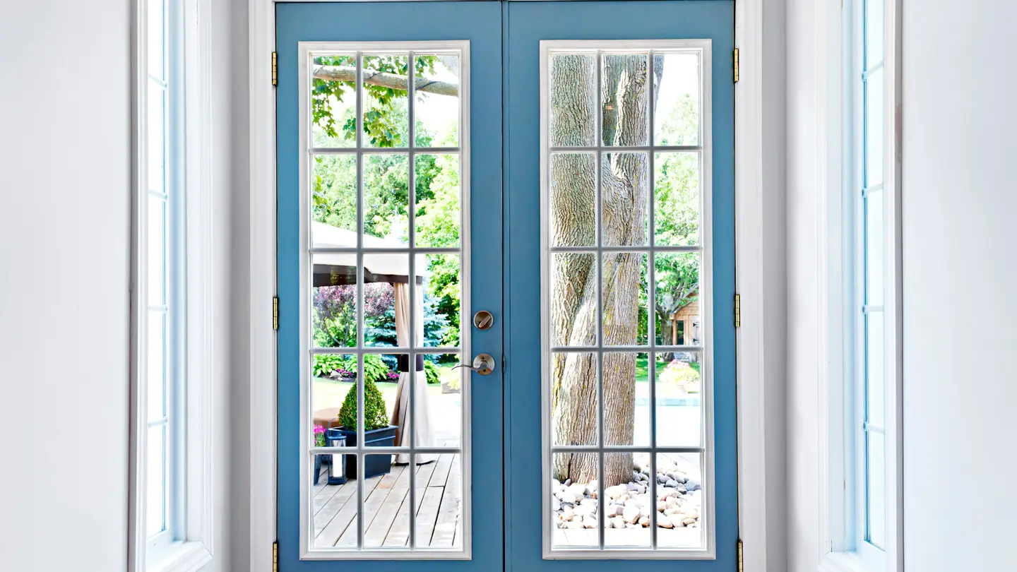 Blue patio door looking out to a yard with a deck and tree. Blue patio door looking out to a yard with a deck and tree.