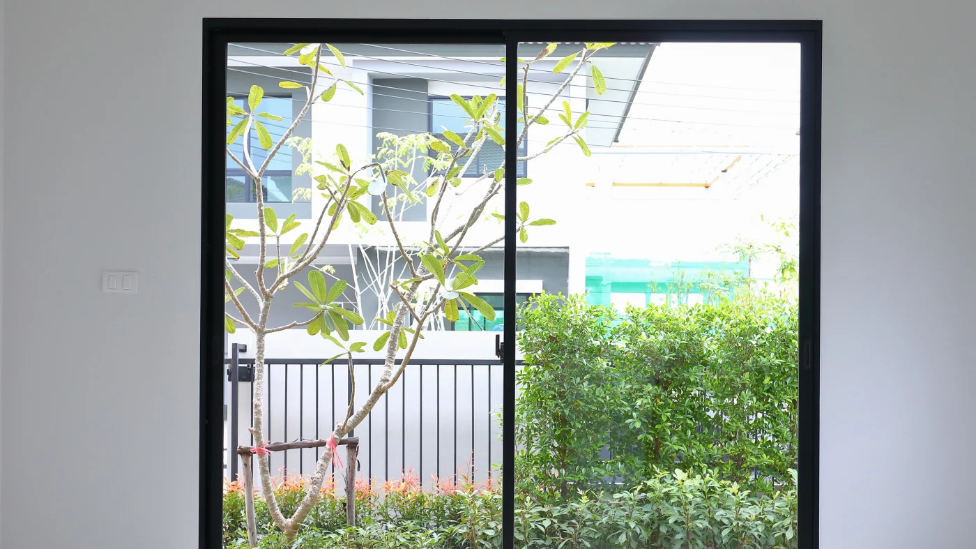 A black trim patio door overlooking trees and other buildings 