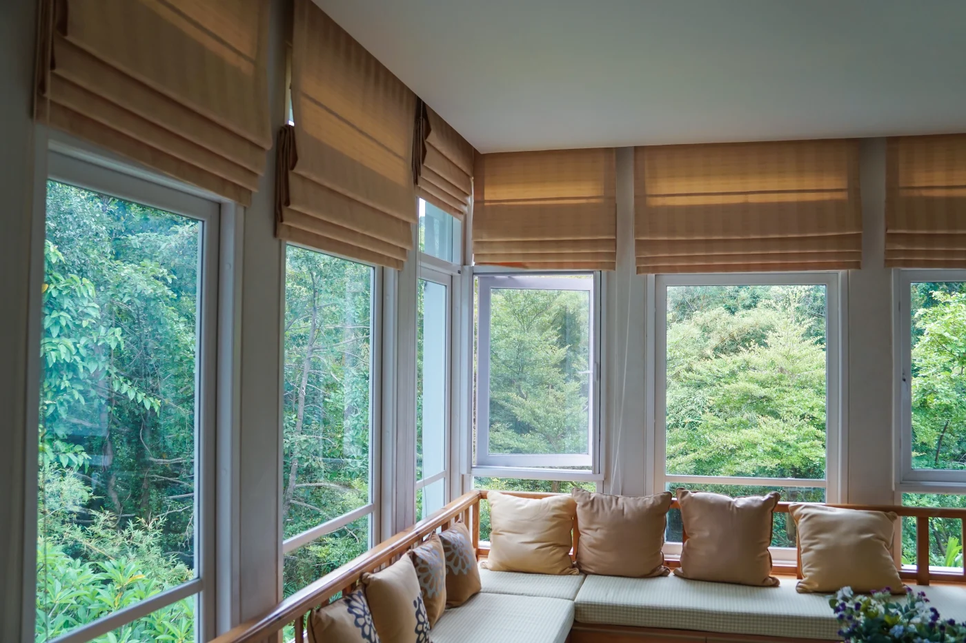Sunroom with spacious windows and brown blinds overlooking greenery