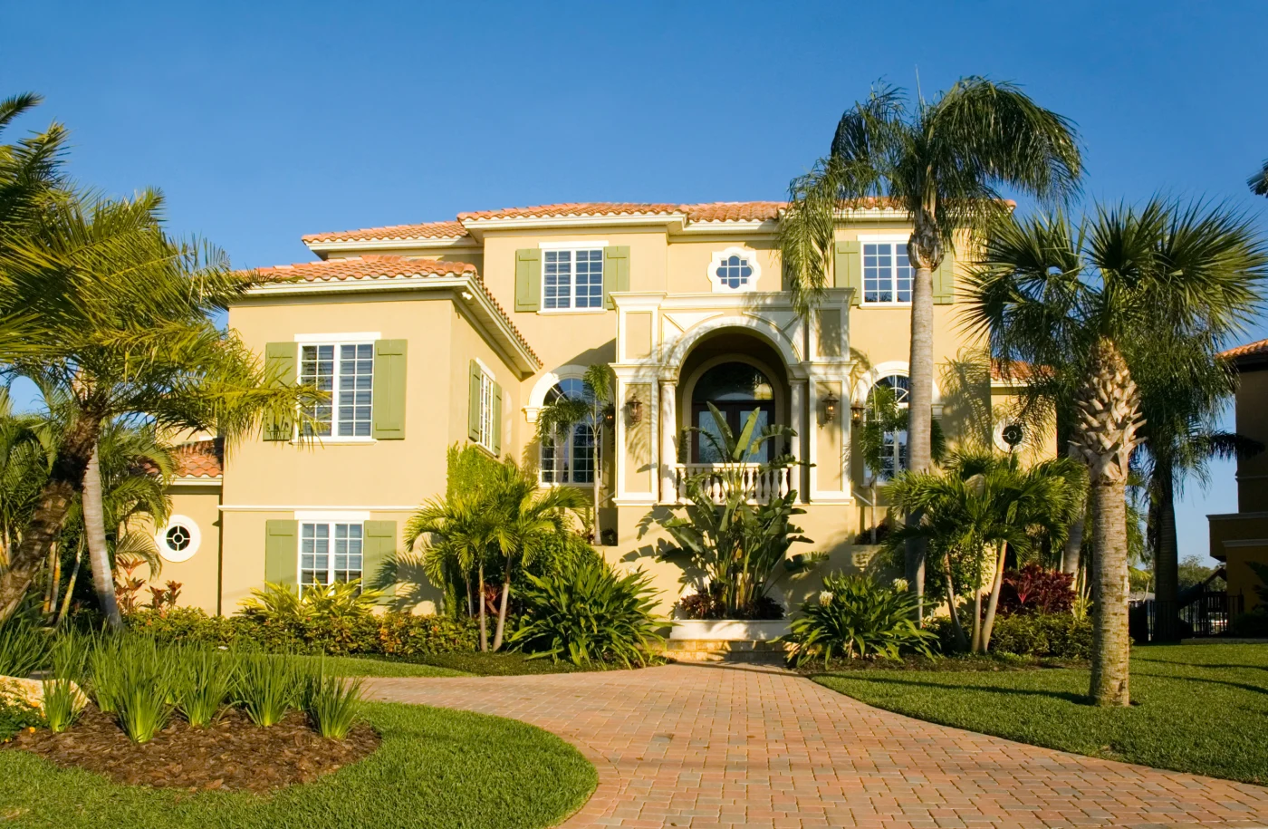 Yellow Florida mansion with spacious windows and palm trees