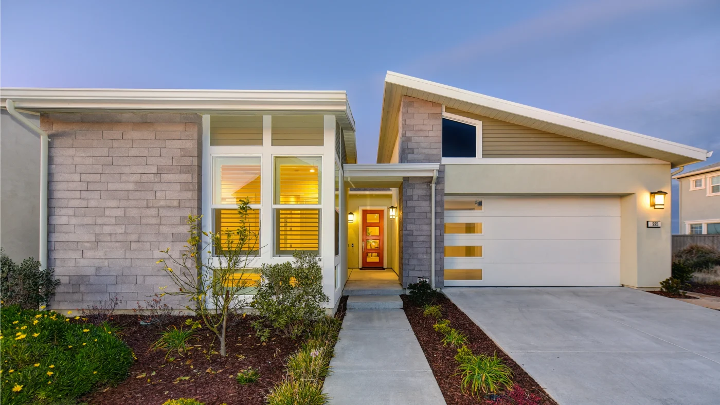 Modern home with stone siding, spacious windows, and contemporary entry door at dusk