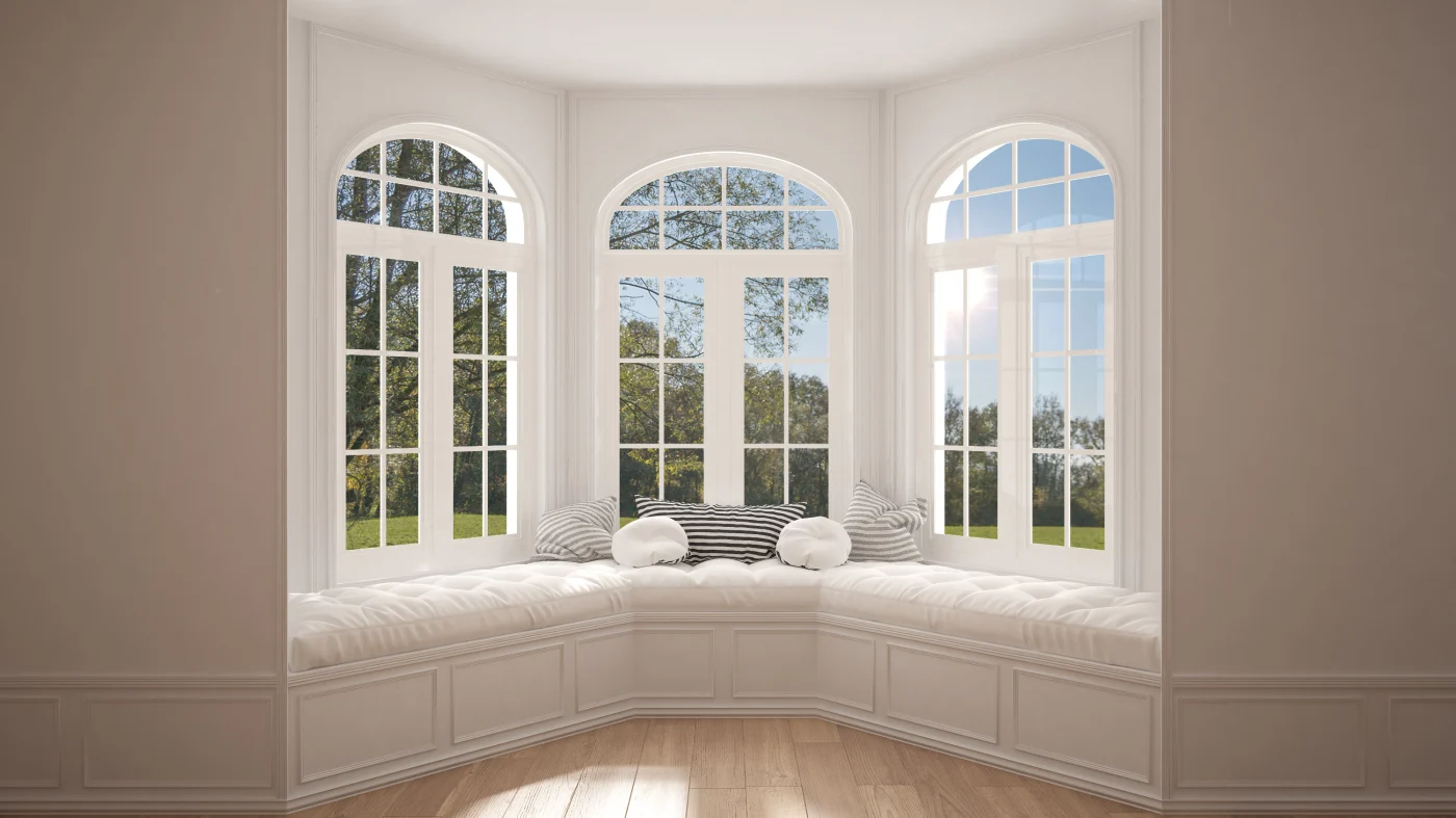 A bay window with reading nook all in light colors and trees out the windows