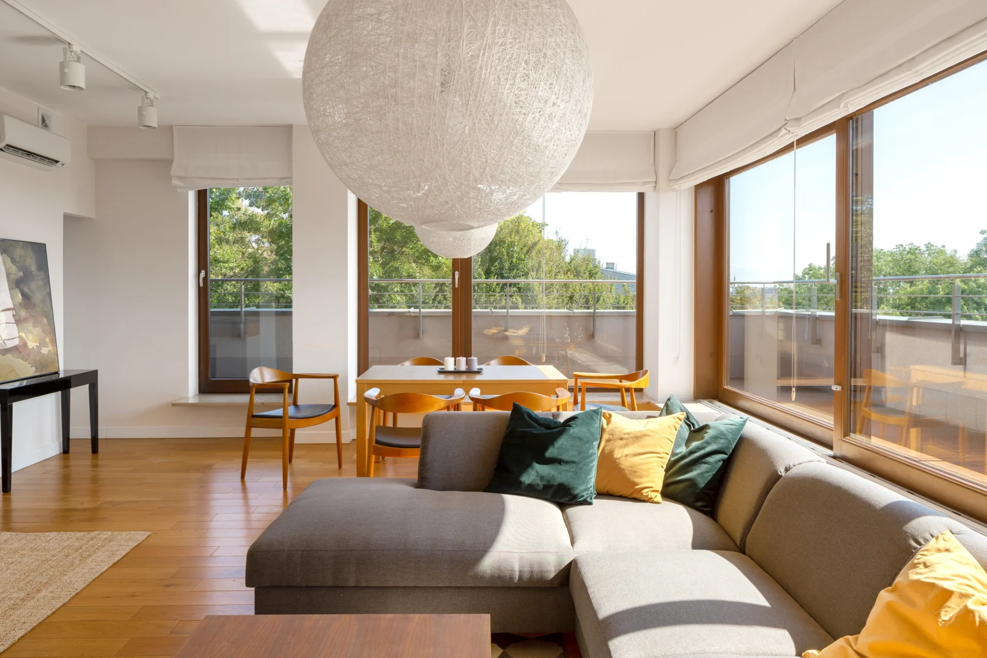 An invitingly decorated living room with large wood-framed replacement windows that look out onto a spacious deck