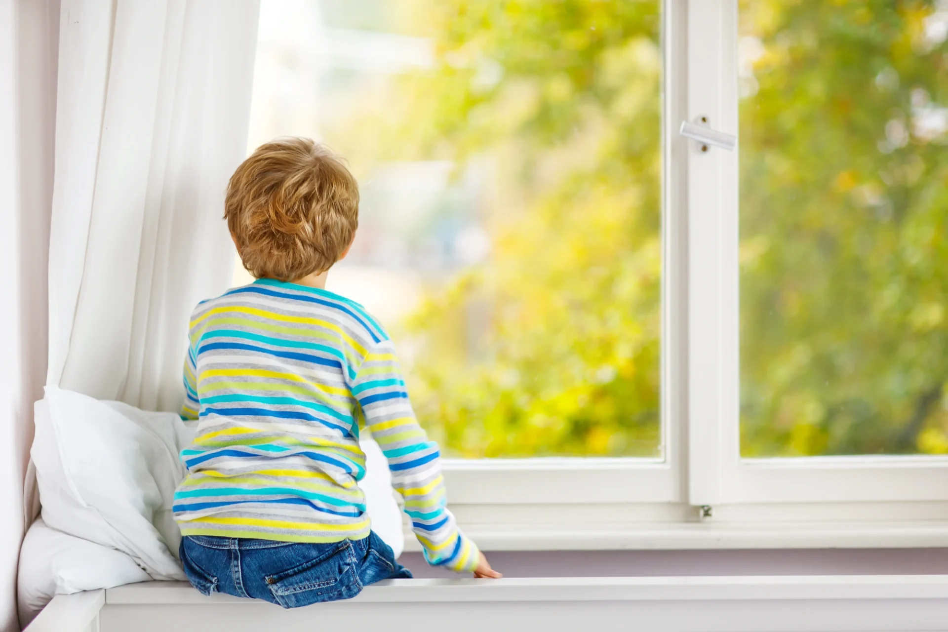 A young boy kooks out at the trees through a new vinyl replacement window in Ortega Forest.