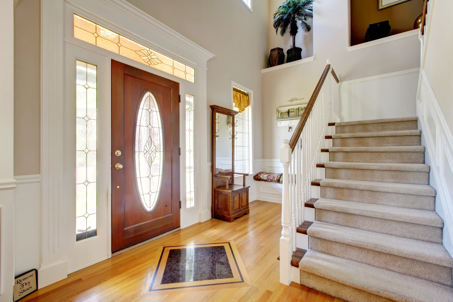 A grand entryway features a striking front door with custom glass. The door has a matching transom and sidelights