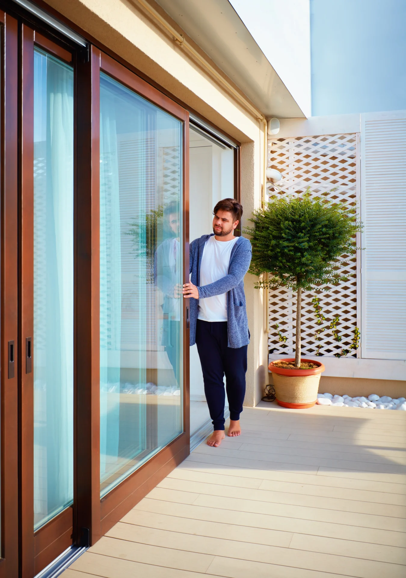A homeowner effortlessly slides open a grand patio door with a wood-grain frame
