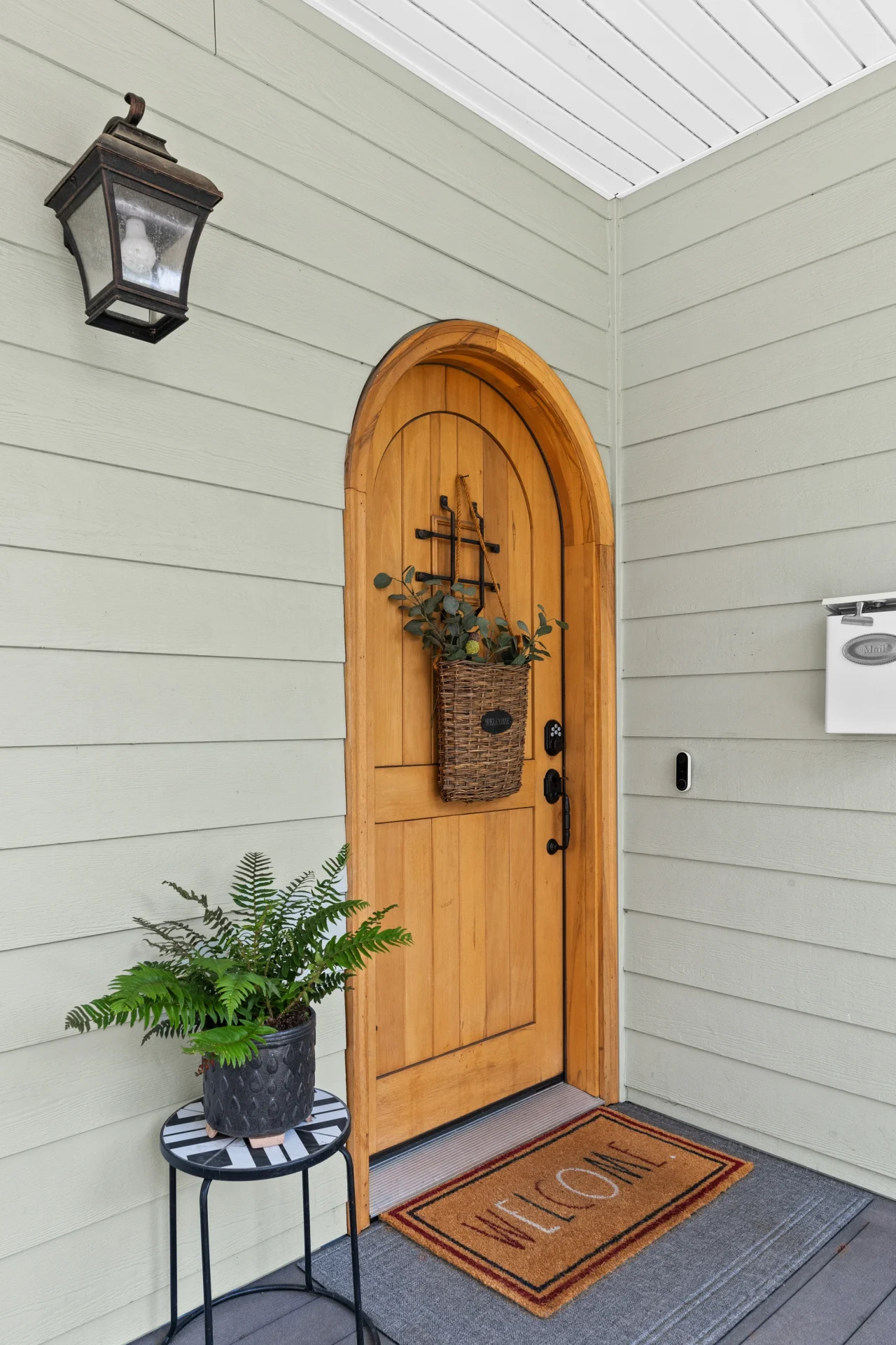 A beautiful arched wooden entry door with a speakeasy grille