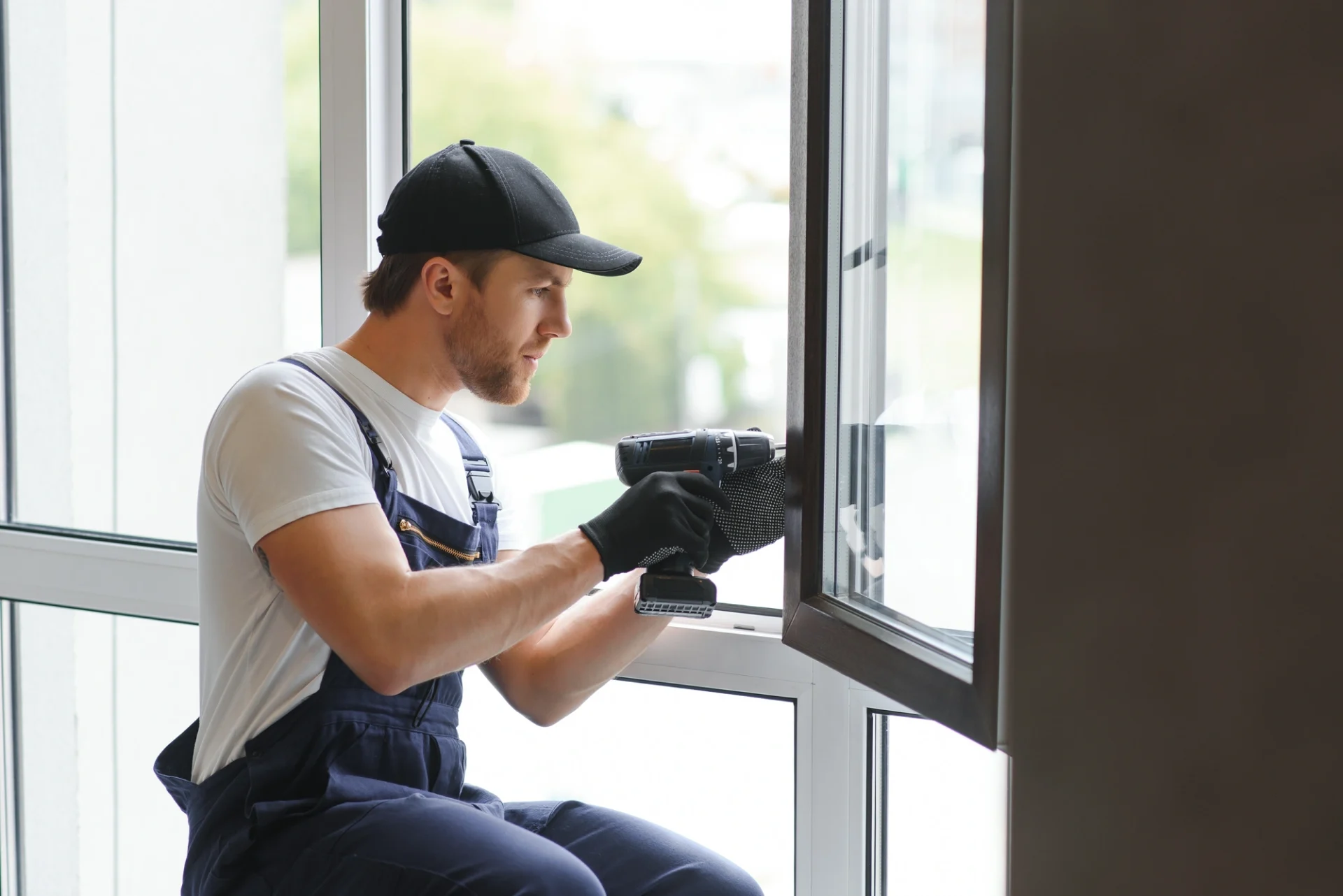 An expert installer carefully uses a drill to fix a replacement window in place