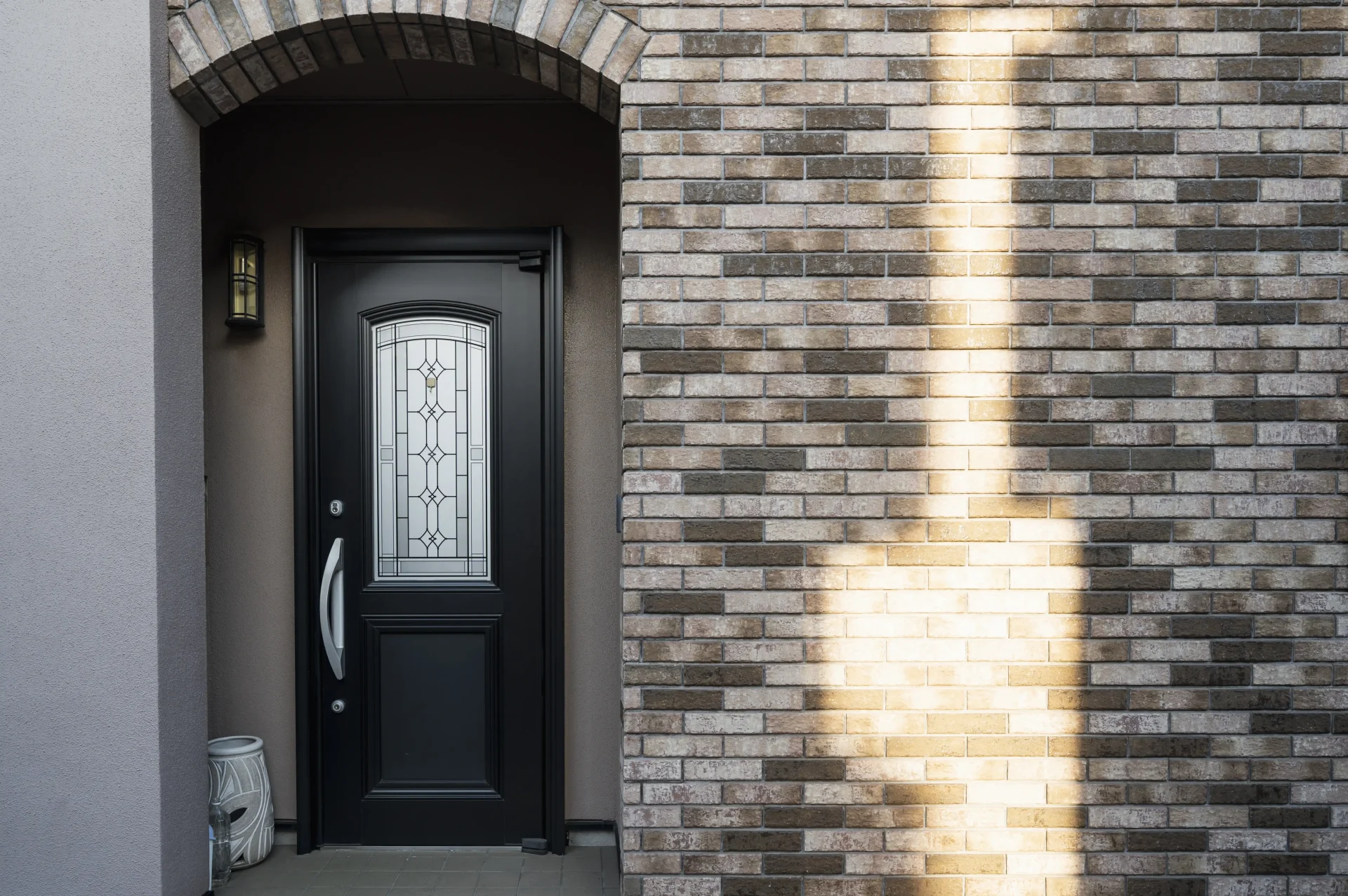 A black door features freshly replaced glass with a classic pattern, frosted for privacy.