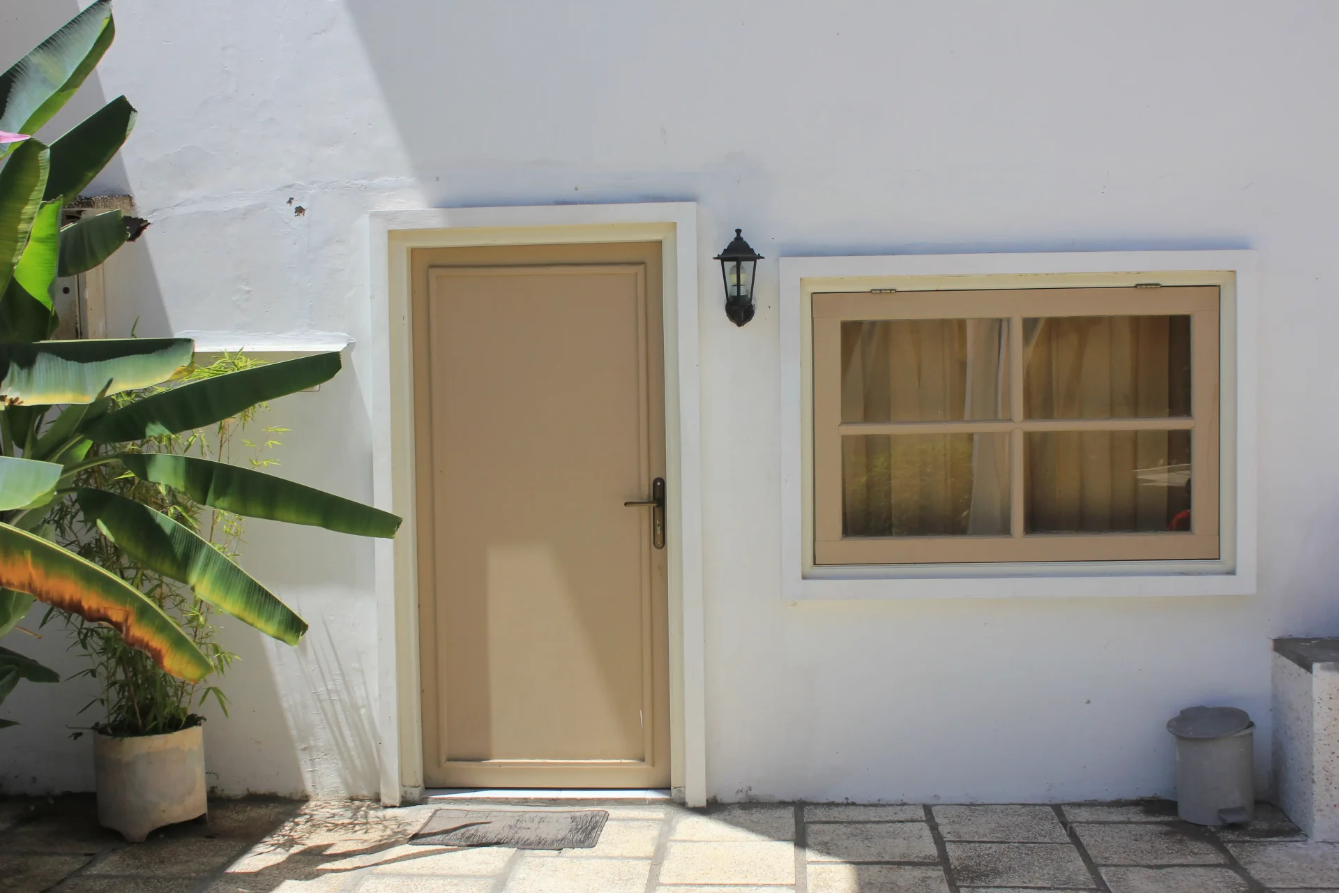 A simple fiberglass door and matching window in beige make a bold statement against stark white walls.