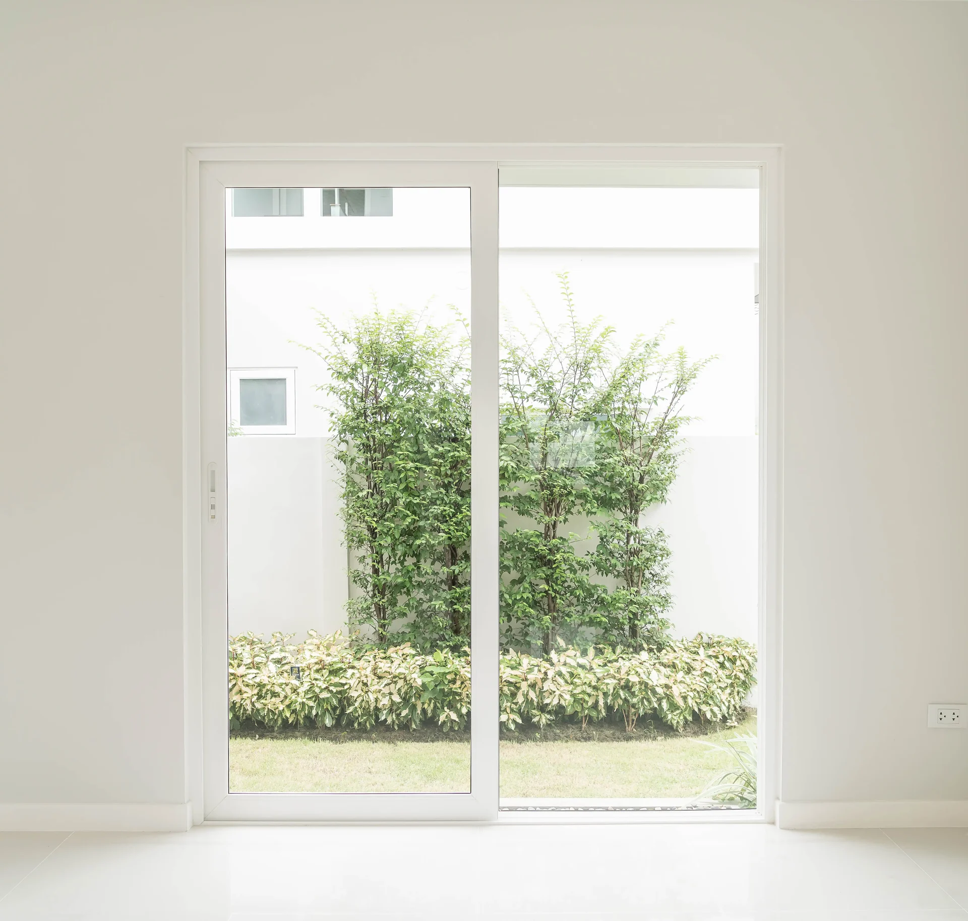 A simple sliding patio door with a white frame blends into the wall, letting the view of the outside become the focal point of the room.