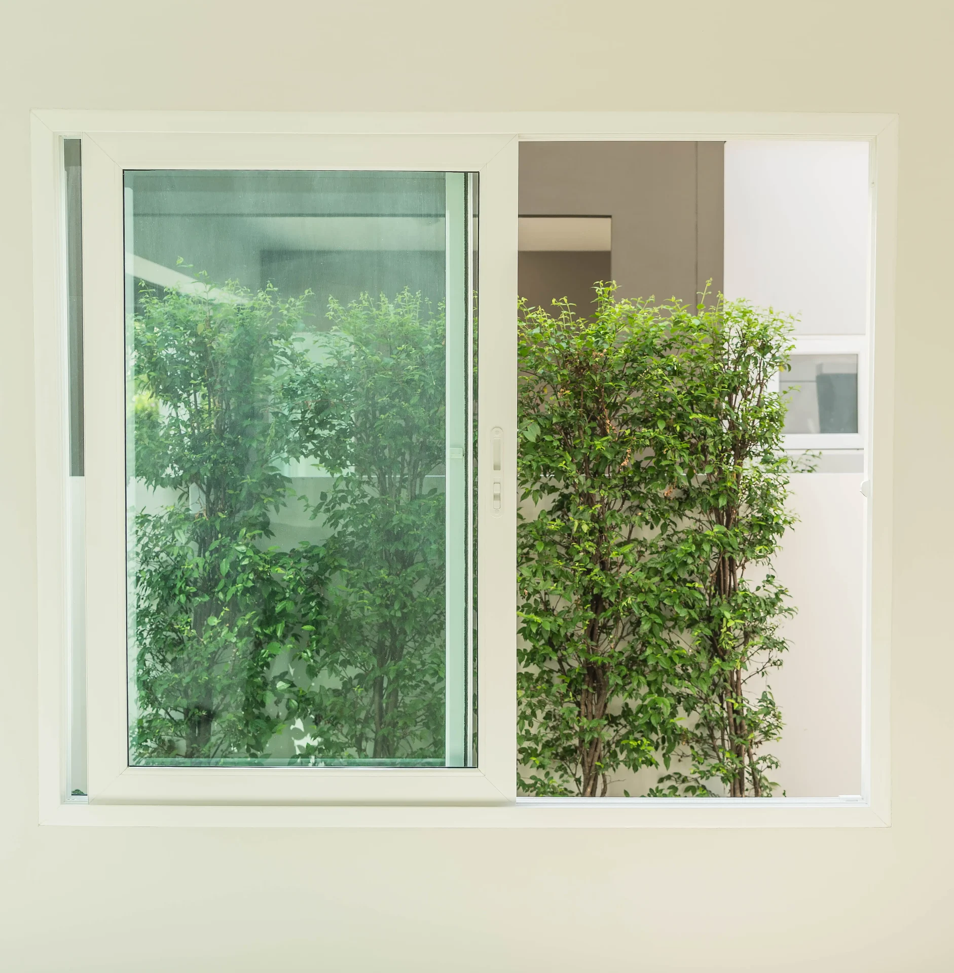 A sleek, white-framed sliding replacement window lets a home’s landscape shine.