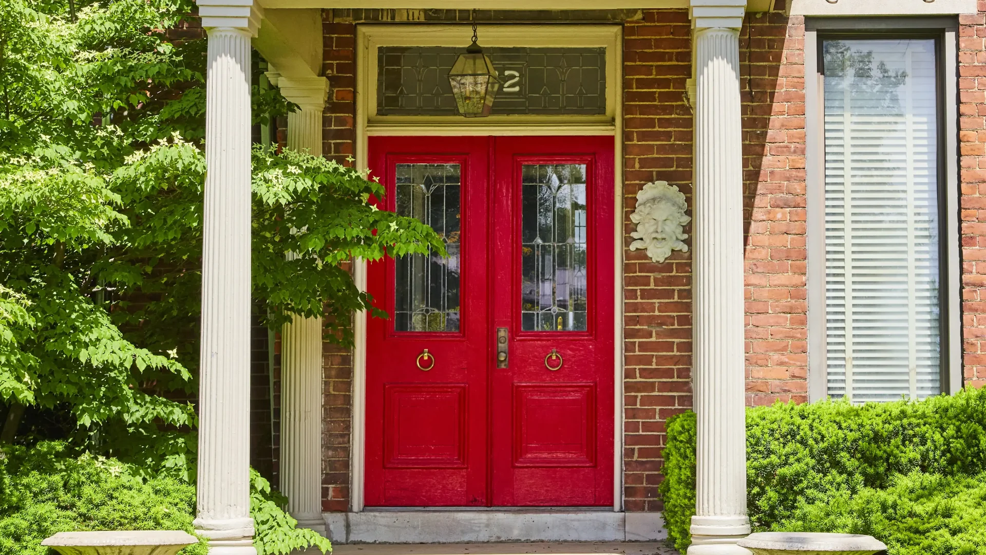 Red double entry doors with glass center on brick home