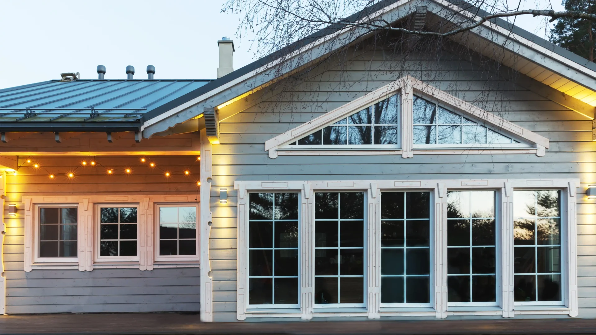 Home with lots of large windows, blue siding, and lights hanging above the window frames