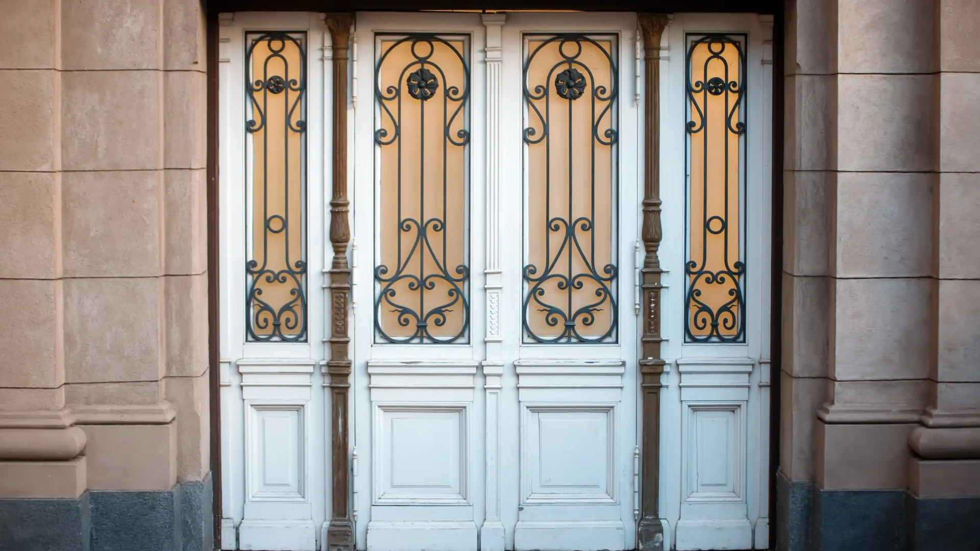 Rustic home exterior with four old white doors with iron ornamentals on them