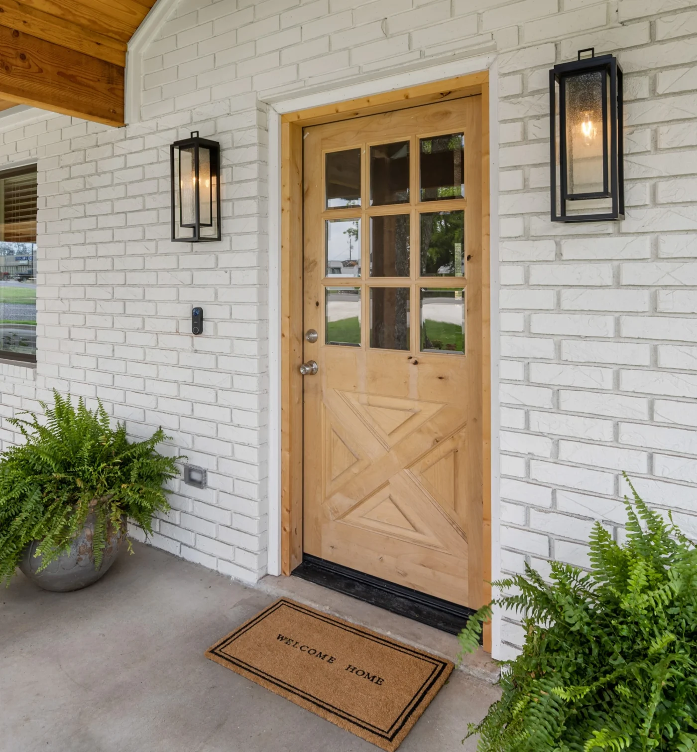 Front of white brick house with a wood front door