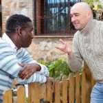 Two neighbors are talking across a fence.