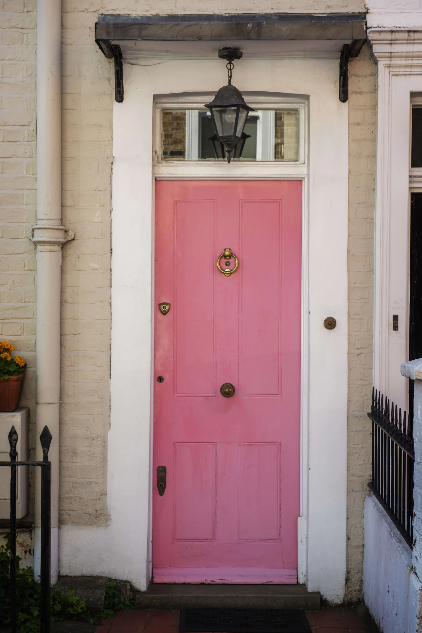 A bright pink fiberglass front entry door with glass inserts above in within the white framing