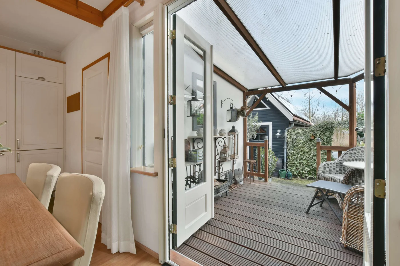 Open French patio doors looking out to a covered patio with wicker furniture