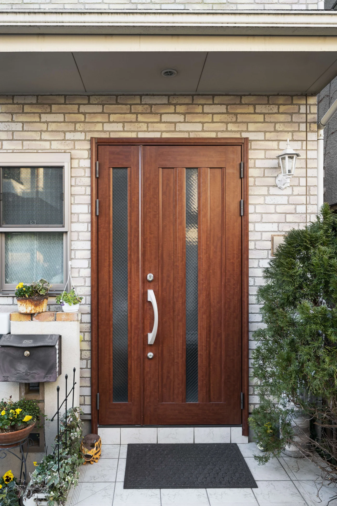 A modern wood door with narrow door glass installations in a brick house.