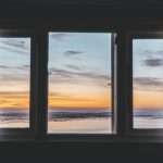 A view of the beach at sunset through impact windows.