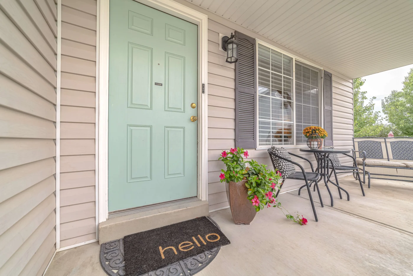 An aquamarine-colored front door on a Florida home with a welcome mat saying "hello"