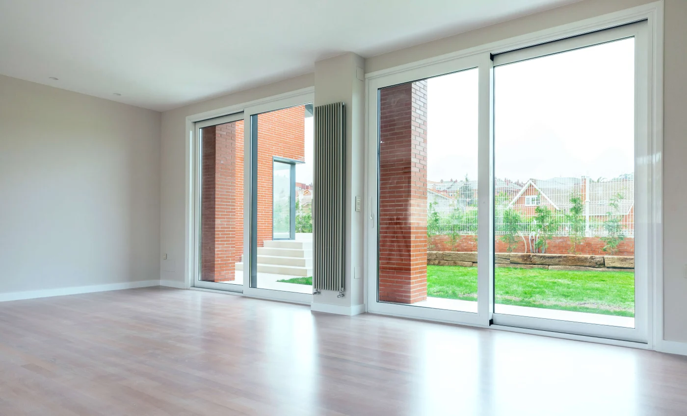 Amazing Patio Doors in Nocatee, FL | Jacksonville Doors & Windows A large, empty sitting room with sliding patio doors overlooking a green lawn on a cloudy day.