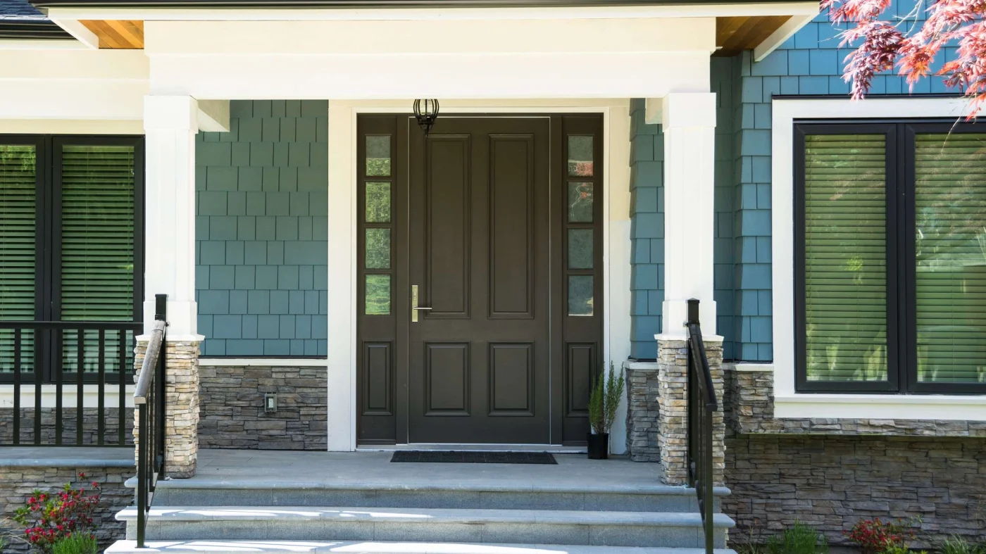 An Amazing Window & Door Company in Nocatee, FL | Jacksonville Doors & Windows A dark, sturdy entry door on a blue house.