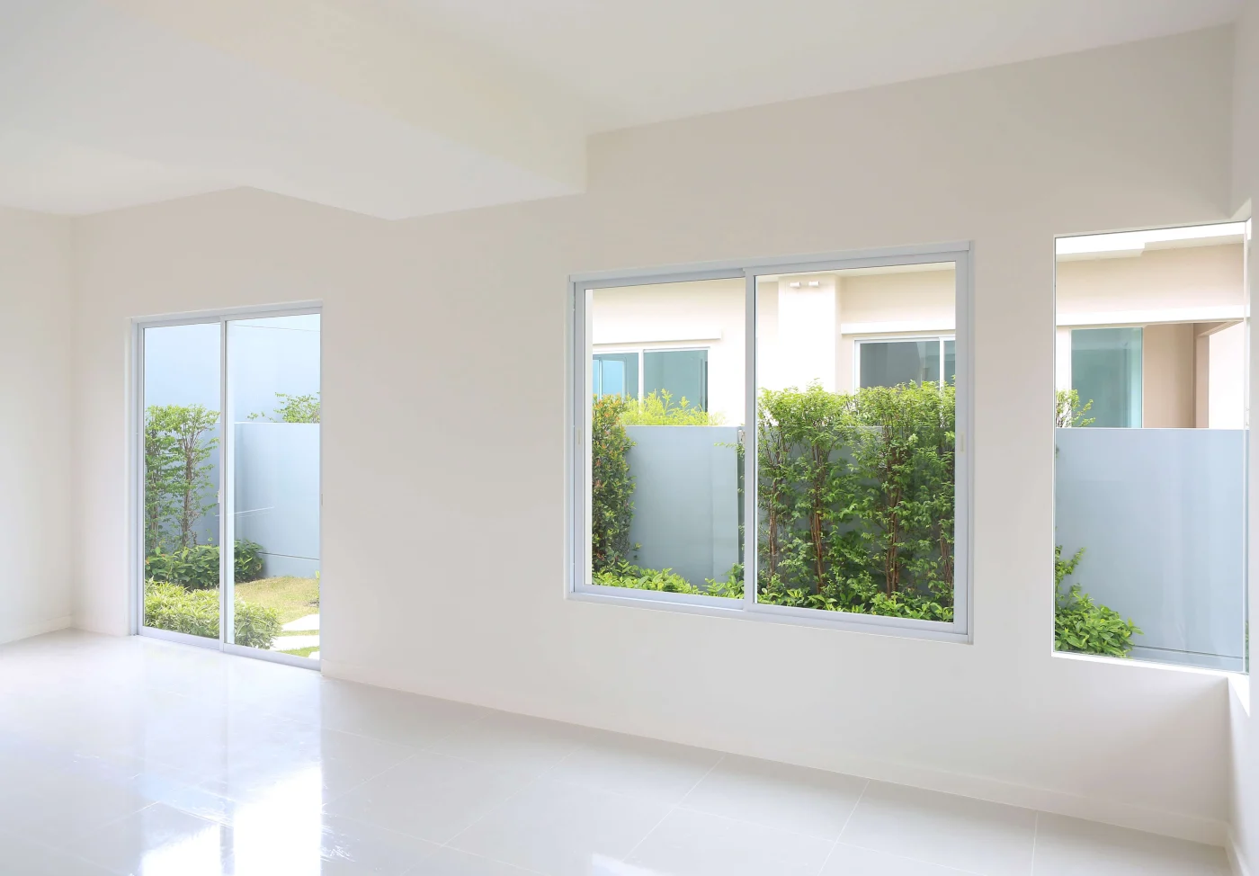 An empty room with large windows and a sliding patio door.