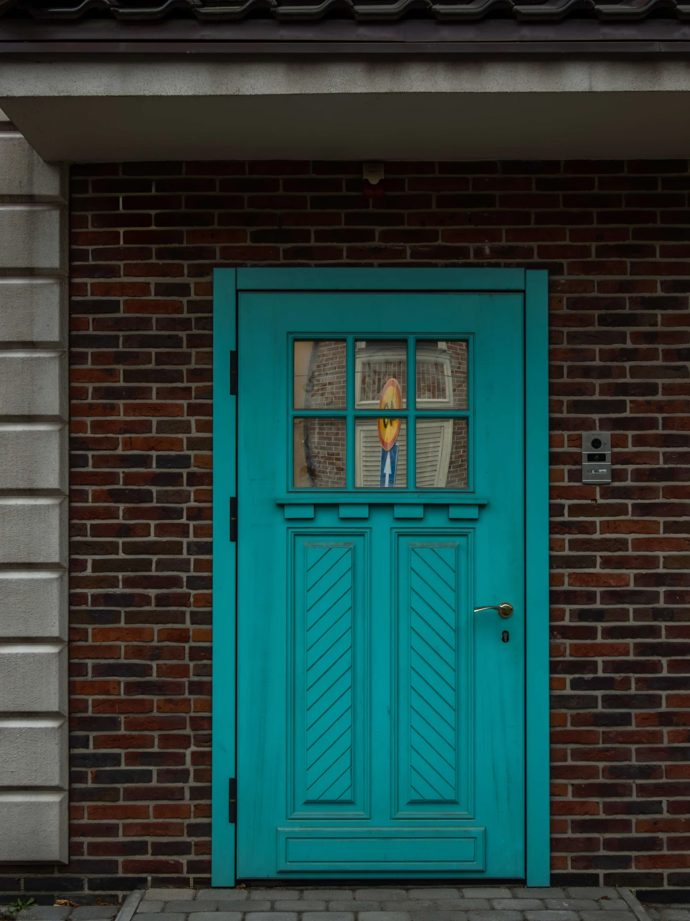A Craftsman-style door painted teal in a brick home.