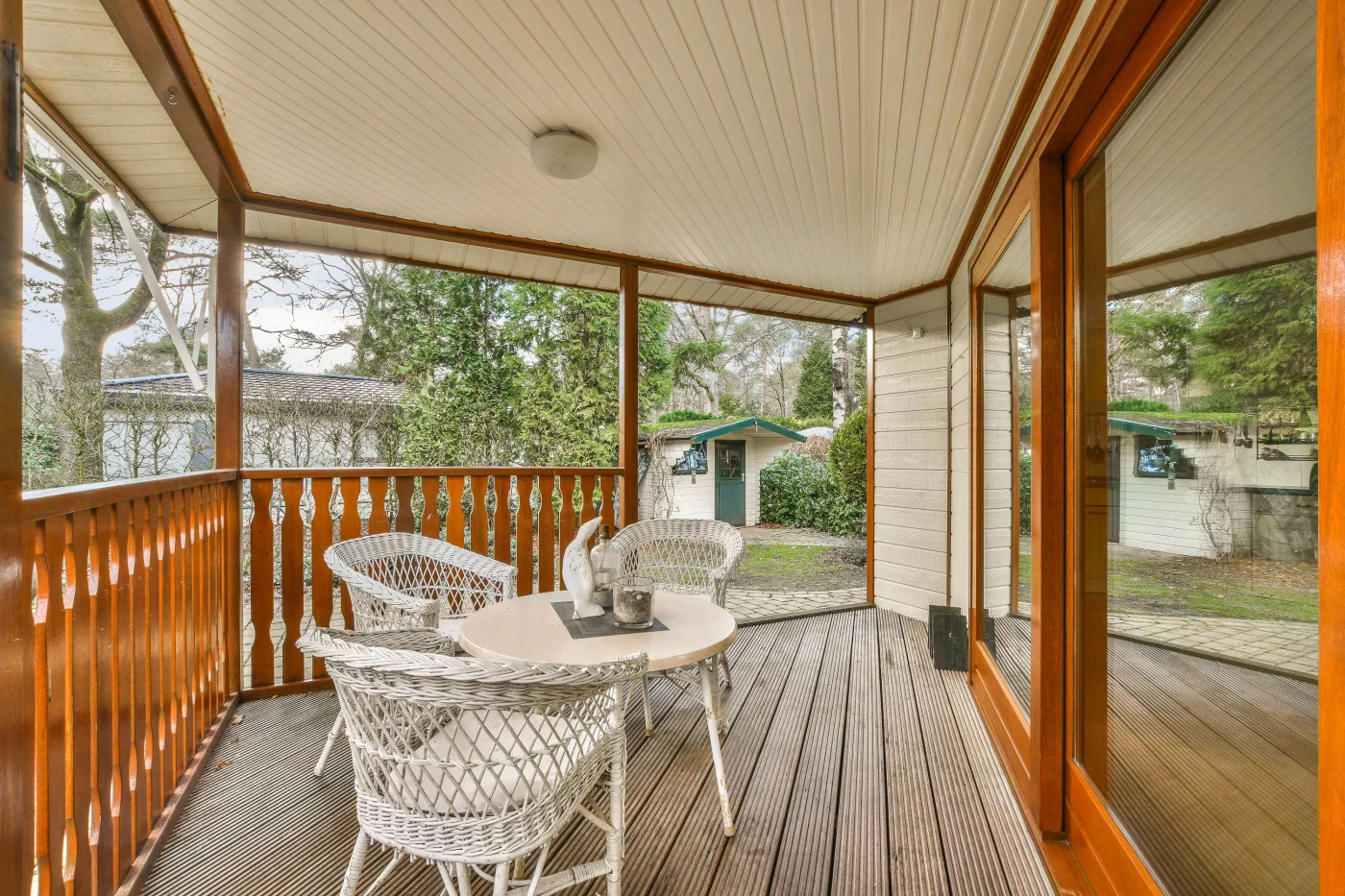 A covered patio with chairs and sliding glass doors framed in fiberglass mimicking wood.